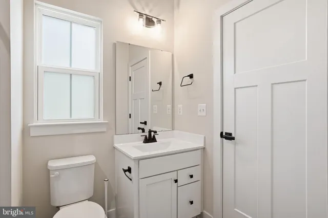 a bathroom with a toilet a sink a mirror a vanity and window