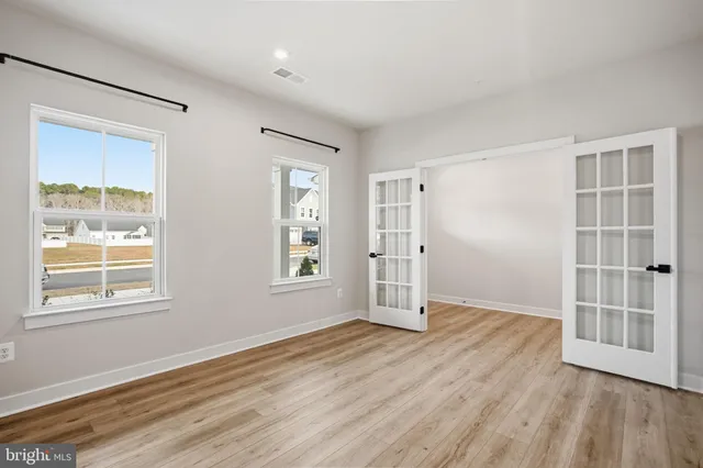 an empty room with wooden floor and windows