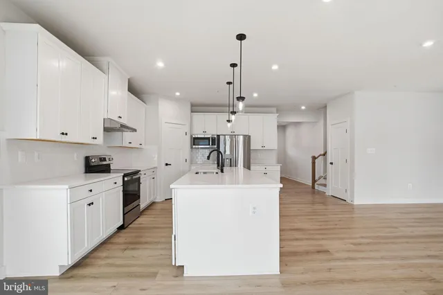 a large white kitchen with wooden floor and a sink