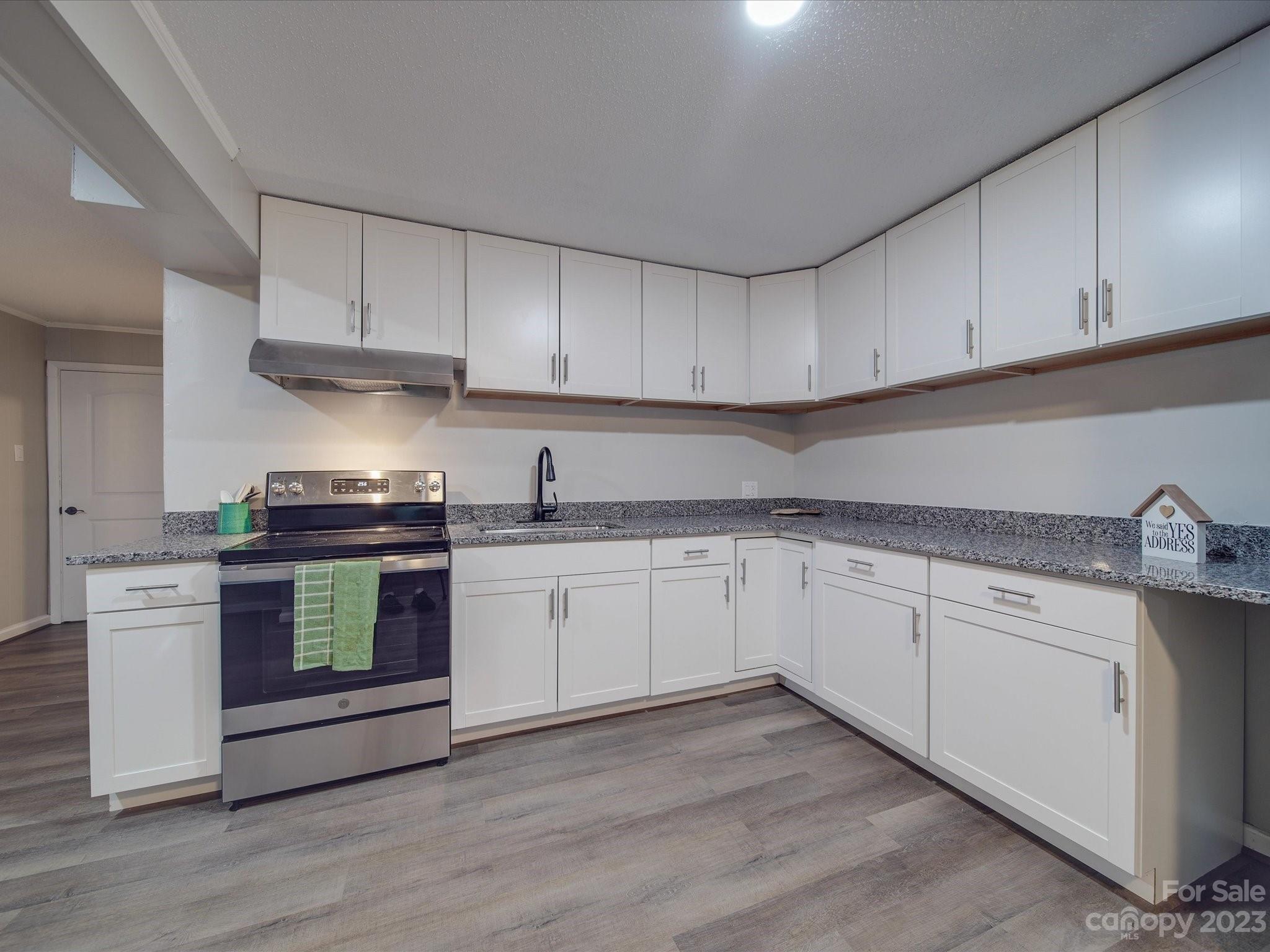 1035 Blake Road Albemarle, NC 28001 - Photo 29 of 45 a kitchen with granite countertop cabinets stainless steel appliances and wooden floor