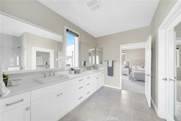 a spacious en suite bathroom with a double vanity sink and mirror