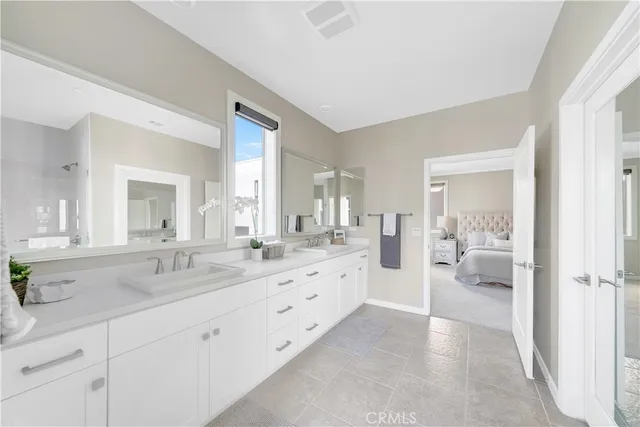 a spacious en suite bathroom with a double vanity sink and mirror