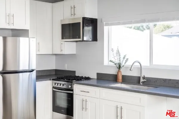 a kitchen with stainless steel appliances granite countertop a refrigerator sink and white cabinets