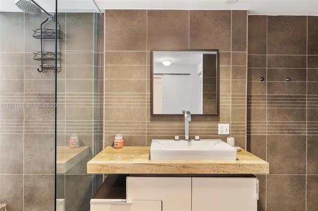 a bathroom with a granite countertop sink a mirror and shower