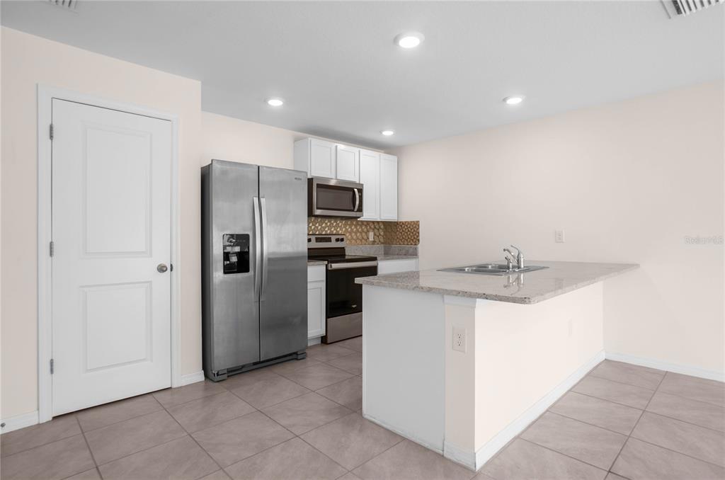 8471 Clearway Drive Wildwood, FL 34785 - Photo 8 of 32 a kitchen with kitchen island a sink stainless steel appliances and counter space