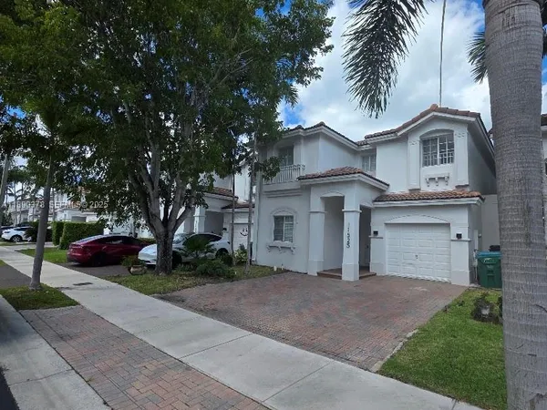 a front view of a house with a garden and trees
