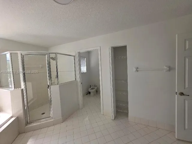 a spacious bathroom with a shower a sink and a large mirror