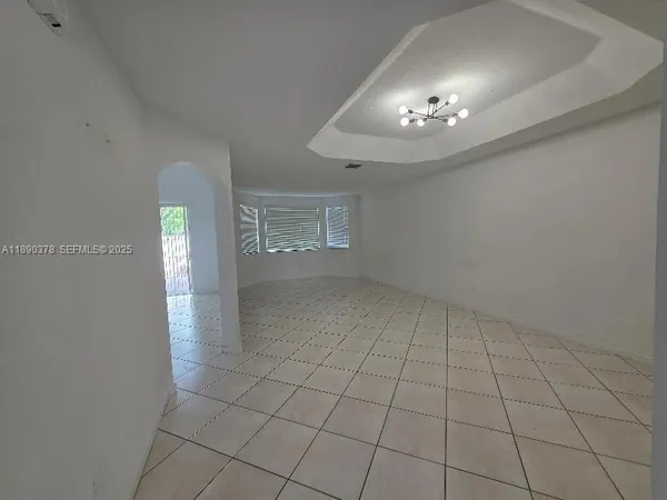 an empty room with chandelier fan and windows