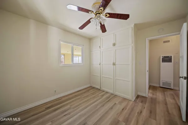 an empty room with wooden floor ceiling fan and windows