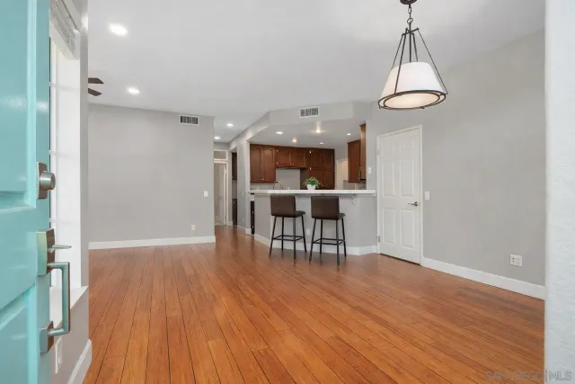 a view of a room with wooden floor a chandelier a wooden table and chairs
