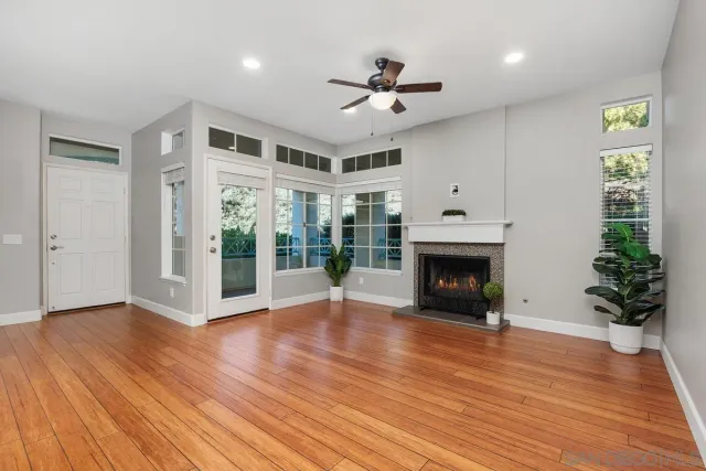 a view of an empty room with wooden floor fireplace and a window