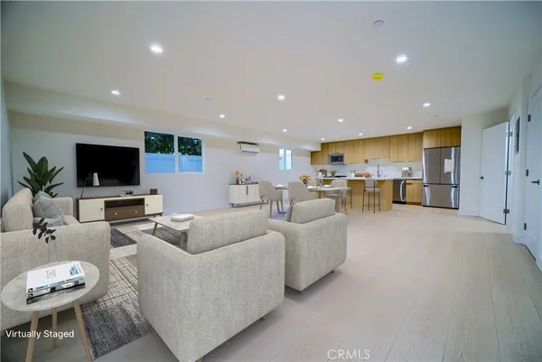 a living room with furniture a flat screen tv and kitchen view