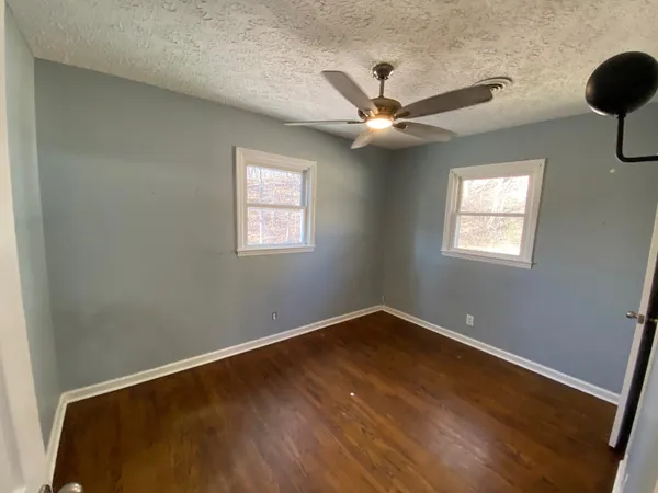 a view of a big room with wooden floor and windows