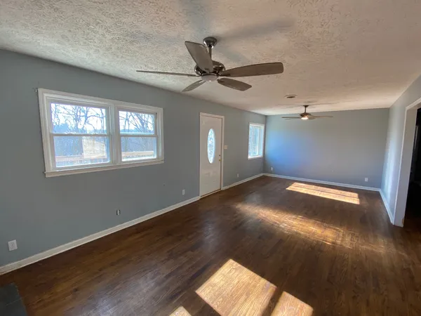 a view of empty room with wooden floor and fan