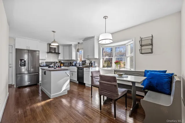 a open kitchen with stainless steel appliances granite countertop a stove a refrigerator a sink dishwasher a dining table and chairs with wooden floor
