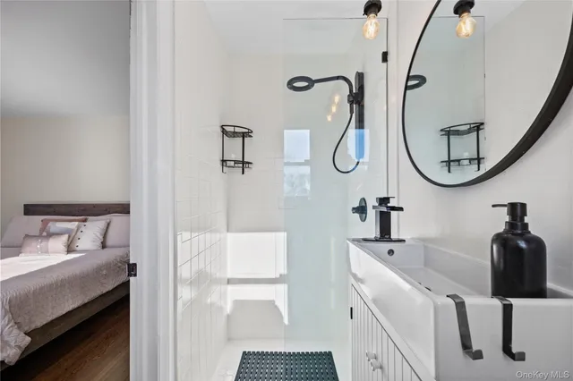 a bathroom with a sink and mirror with bathtub