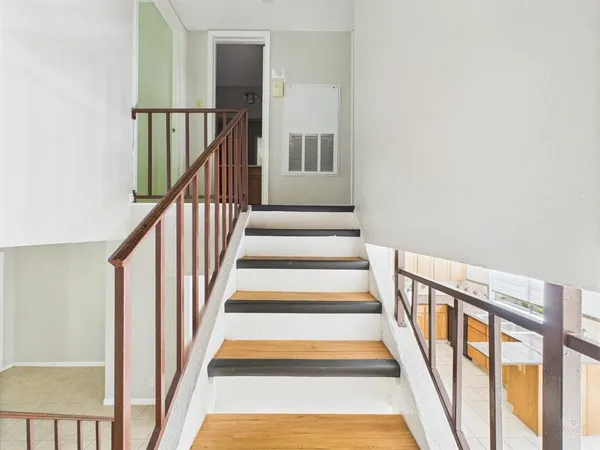 a view of staircase with lots of frames on wall and wooden floor