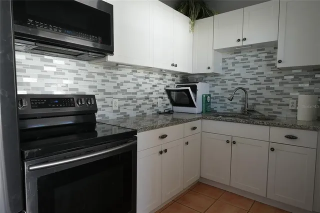 a kitchen with white cabinets and black appliances