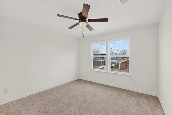 an empty room with windows and fan