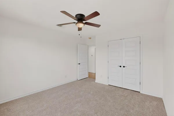 an empty room with windows and fan