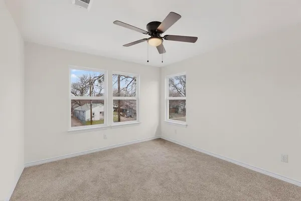 an empty room with window and ceiling fan