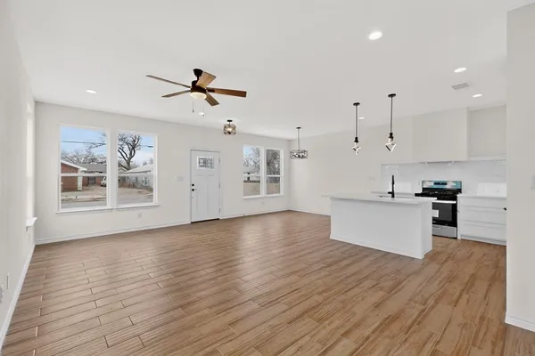 a view of a kitchen with stainless steel appliances granite countertop a sink a refrigerator and a wooden floor