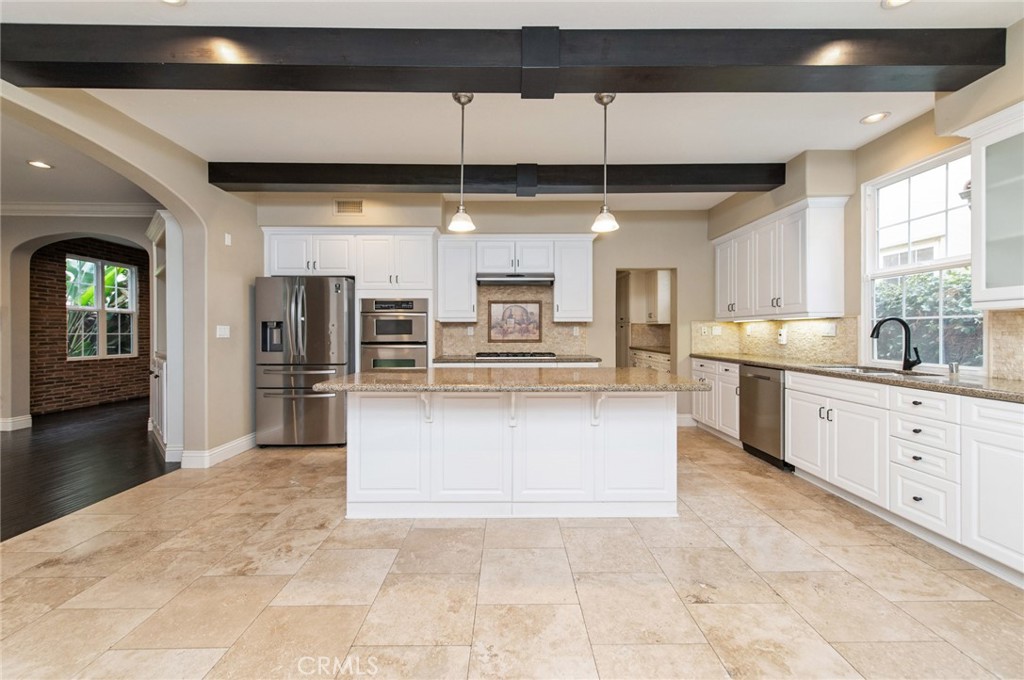 26 Secret Garden Irvine, CA 92620 - Photo 11 of 38 a large white kitchen with kitchen island a large counter space a sink appliances and cabinets