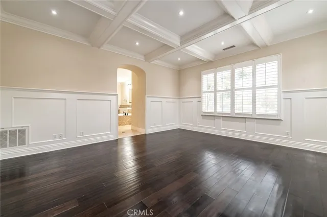 an empty room with wooden floor and windows with curtains
