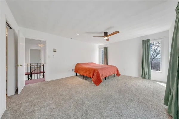 a bed sitting in a spacious bedroom next to a window
