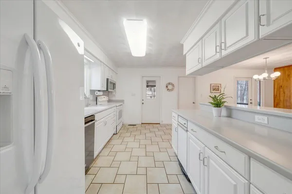 a large white kitchen with granite countertop a sink a window and stainless steel appliances