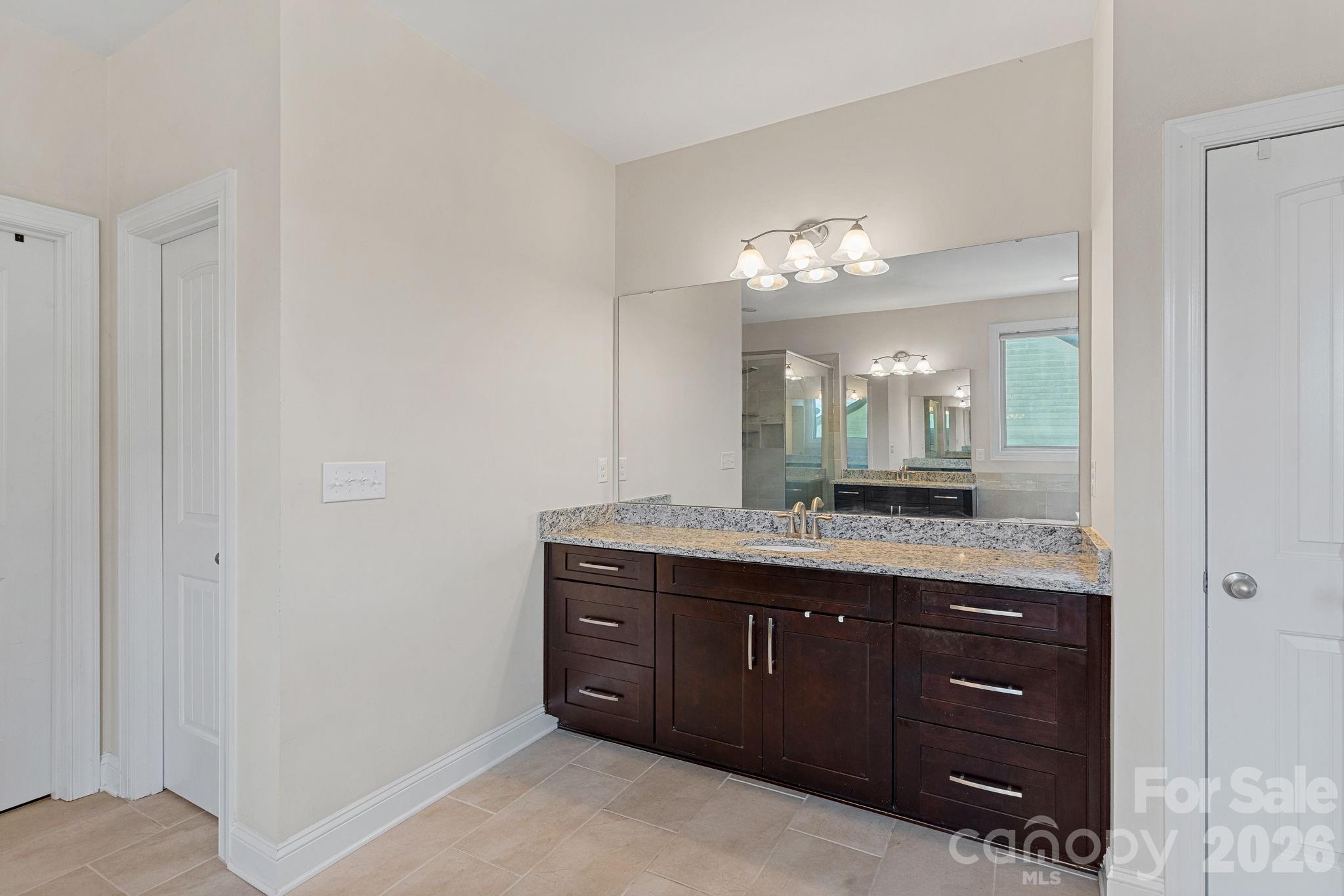 897 Tyne Drive Fort Mill, SC 29715 - Photo 31 of 46 a spacious bathroom with a granite countertop sink a mirror and a vanity