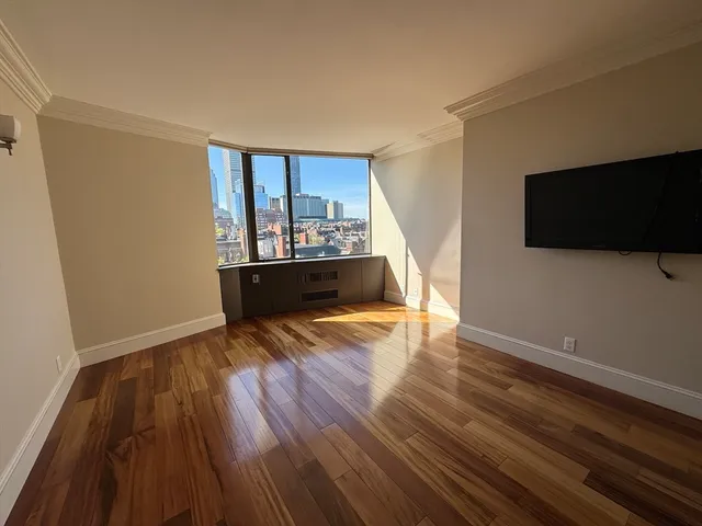 a view of empty room with wooden floor and fan