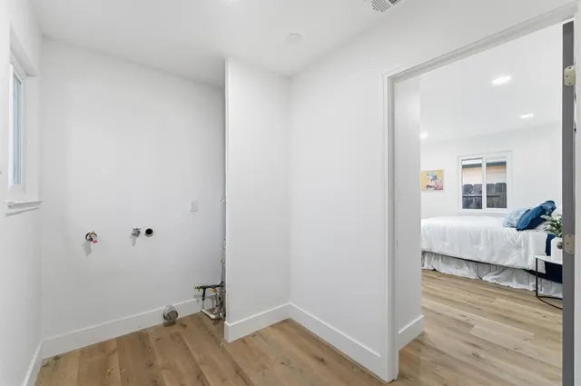 a view of a bedroom with wooden floor and white walls