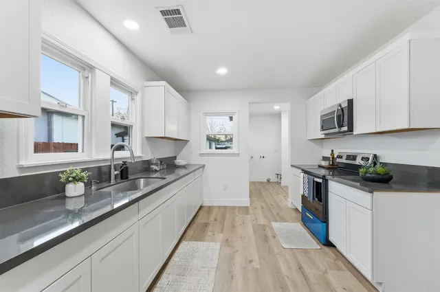 a large kitchen with stainless steel appliances granite countertop a lot of counter space and wooden floors