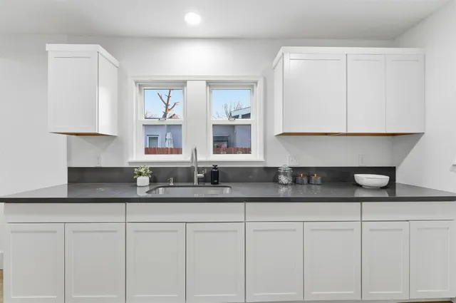 a kitchen with granite countertop white cabinets and a sink