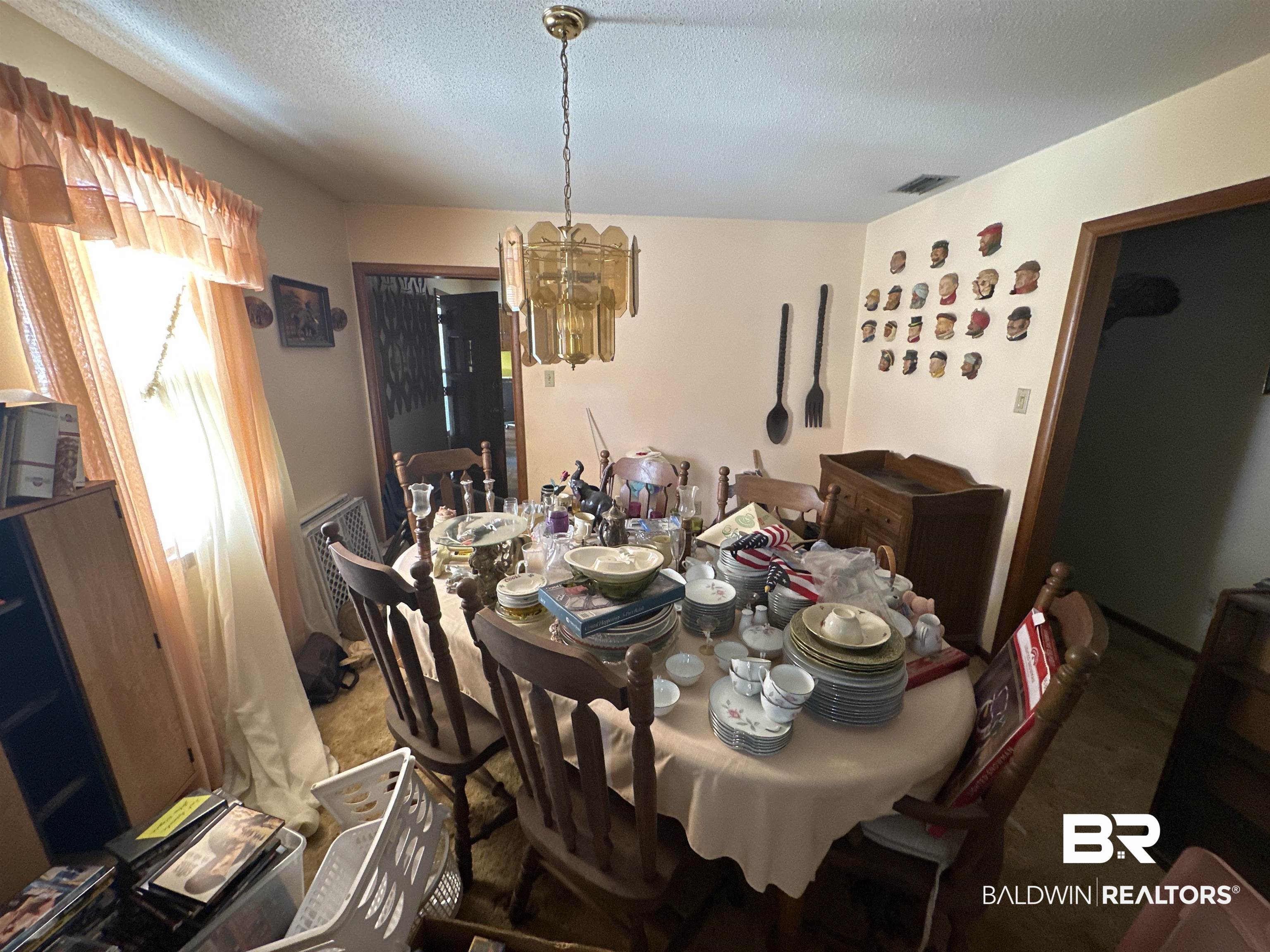 9520 C Four Mile Road Irvington, AL 36544 - Photo 14 of 32 Carpeted dining room featuring a chandelier and a textured ceiling