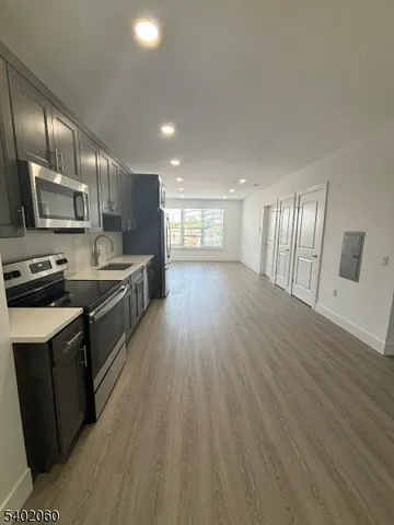 a large kitchen with stainless steel appliances a large counter top a stove and a wooden floors