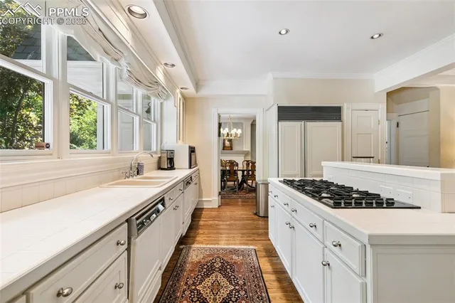 a large white kitchen with stainless steel appliances granite countertop a stove and a large window
