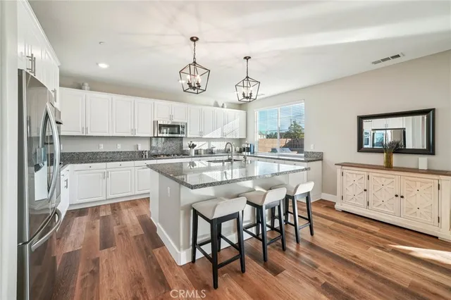 a kitchen with stainless steel appliances kitchen island granite countertop a stove a sink and a refrigerator
