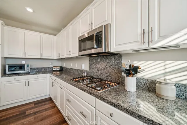 a kitchen with stainless steel appliances granite countertop a stove a white cabinets and a sink