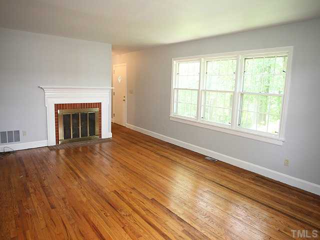 2452 Oxford Road Raleigh, NC 27608 - Photo 3 of 25 an empty room with wooden floor fireplace and windows
