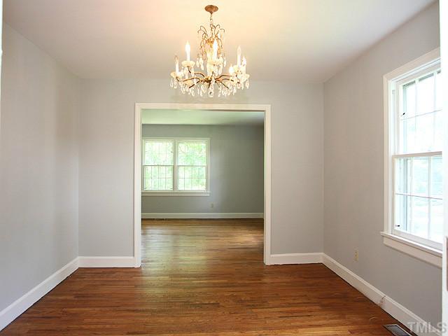 2452 Oxford Road Raleigh, NC 27608 - Photo 6 of 25 an empty room with wooden floor chandelier and windows