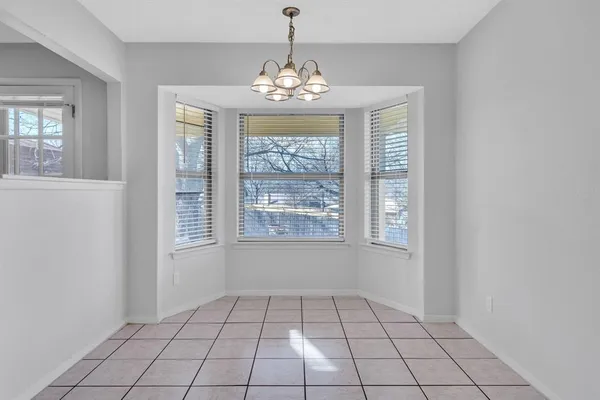 a view of an empty room with window and chandelier