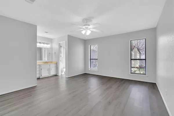 an empty room with wooden floor chandelier fan and windows