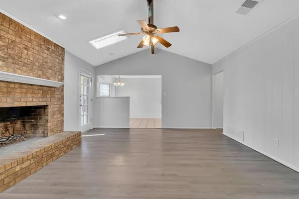 a view of a room with wooden floor fireplace and windows