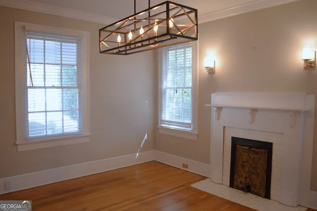 an empty room with wooden floor fireplace and windows