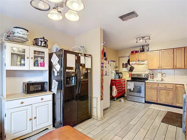 a kitchen with stainless steel appliances granite countertop a stove a sink dishwasher and a refrigerator with wooden cabinets