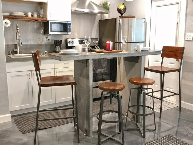 a kitchen with stainless steel appliances kitchen island granite countertop dining table chairs and granite counter tops