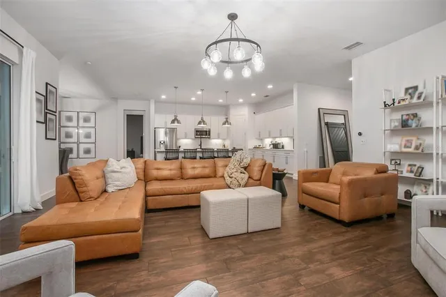 a living room with furniture kitchen view and a chandelier