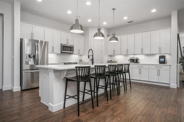 a kitchen with stainless steel appliances a dining table chairs microwave and sink